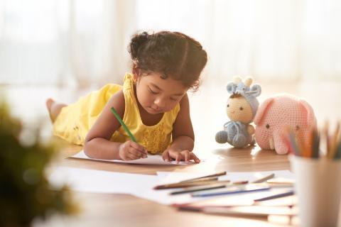 Child lying on the floor and coloring pages